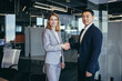 © Liubomir - Asian businessman shakes hands with business woman employee, happy team of workers looking at camera and smiling, successful conclusion of negotiations