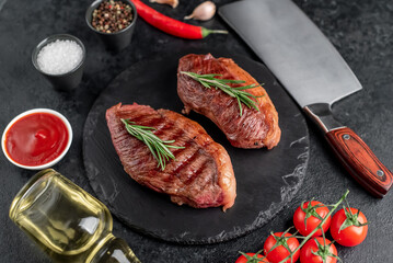 Two grilled picanha steaks with spices on a stone background