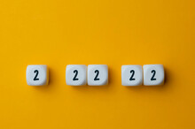 The Unique Date Is February 22, 2022. Numbers 2 22 22 On White Cubes Shapes On Yellow  Background.  
