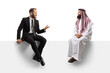 © Ljupco Smokovski - Businessman and a saudi arab man having a conversation seated on a blank panel