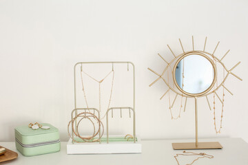 Jewelry box, stand and mirror on white table near light wall