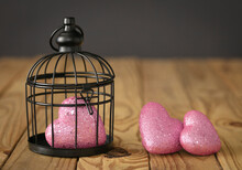 Concept About Relationship Problems. Three Pink Hearts With One Of Them Capture In A Black Cage.