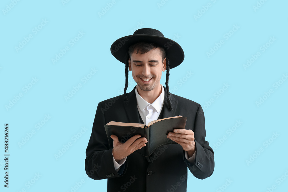 Hasidic Jewish man with Torah on color background