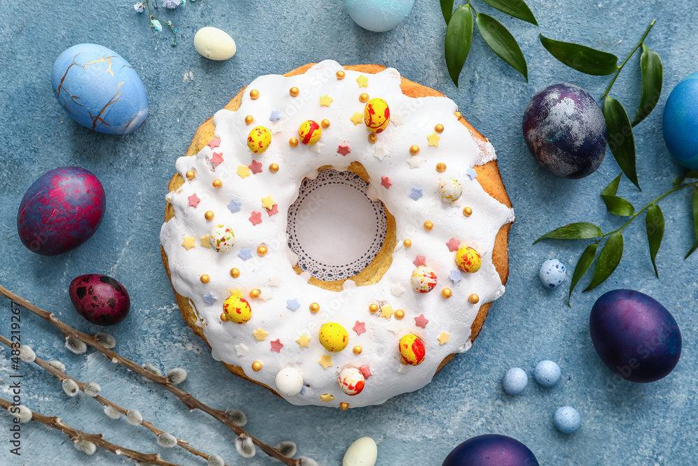 Tasty Easter cake and eggs on blue background