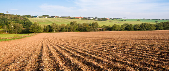 Sticker - panorama of spring plowed fields and a village on the horizon