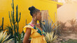 portrait of a beautiful African-American woman with cactuses by a yellow wall in the background. ethno concept