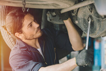 Caucasion Male Mechanic Car Service Staff Worker Working In Garage Fix Drive Shaft Problem