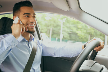 Wall Mural - Positive arab guy having phone conversation while driving car