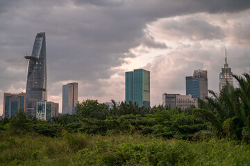  Picture of skyscrapers at sunset in the park with green grass and trees. View in metropolis with modern buildings. High quality photo