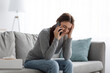Leinwandbild Motiv Despair upset caucasian millennial woman suffering from depression, crying and talking on phone at home