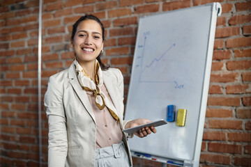 Wall Mural - Young happy businesswoman with digital tablet in meeting room looks at camera.