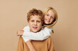 © Tatiana - Boy and girl standing next to posing emotions beige background