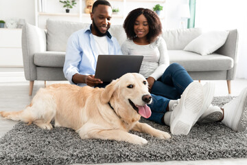 Wall Mural - Black couple at home using pc laptop relaxing with dog