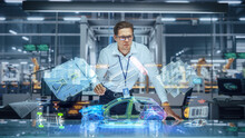 Sustainable Industrial Design: Portrait Of Modern Automotive Engineer Using Augmented Reality To Construct 3D Hologram Model Of High-Tech Electric Car. Automated Vehicle Manufacturing Facility
