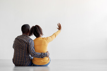 Wall Mural - African american husband and wife sit on floor planning interior at flat, choosing design of new apartment