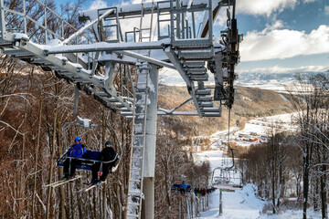 Skiers sitting on ski-lift chair or chairlift