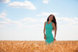 Happy woman enjoying the life in the field. Nature beauty, blue sky, white clouds and field with golden wheat. Outdoor lifestyle. Freedom concept. Woman walk in summer field