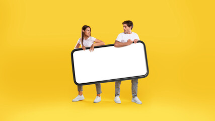 Wall Mural - Couple holding big white empty smartphone screen