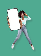 new mobile app, special offer. jumping black lady showing smartphone with empty screen on turquoise 