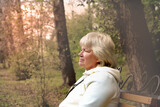 Fototapeta Las - Thoughtful senior woman in hoodie  looking away in park