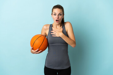 Canvas Print - Young woman playing basketball isolated on blue background surprised and shocked while looking right