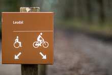 Foreground Focus Of A Hiking Sign Indicating: One Lane For Wheelchairs And The Other For Bicycles With A Blurred Background, Leudal Nature Reserve In Midden-Limburg In The Netherlands