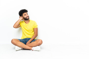 Young Moroccan handsome man sitting on the floor over isolated background thinking an idea