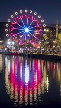 Cityscape With Reflections In The Water Of The Port Of Barcelona,Catalonia,Spain. Ferris Wheel Rotating At Dusk With Many Colorful Led Lights In Motion With Long Exposure.Video In Vertical Format.