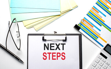 NEXT STEPS text on paper sheet with chart,color paper and calculator