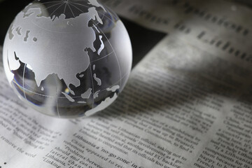 ガラスの地球儀と新聞　グローバルな事象のイメージ　glass globe(Asia and Oceania) on  newspapers