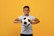 © Prostock-studio - Cheerful black school boy holding soccer ball