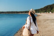 © Syda Productions - people, summer holidays and leisure concept - happy smiling young woman in white shirt and straw hat with bag walking along beach