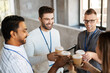 © Syda Productions - business, people and corporate concept - happy smiling colleagues with conference badges drinking takeaway coffee at office