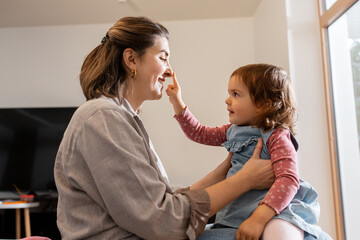 Canvas Print - family, hygge and people concept - happy mother and little daughter playing at home