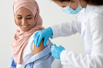 Closeup Shot Of Female Doctor Making Coronavirus Vaccine Injection To Muslim Woman