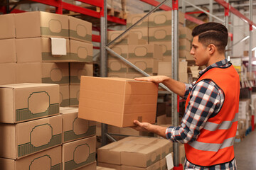 Wall Mural - Worker stacking cardboard boxes in warehouse. Wholesaling