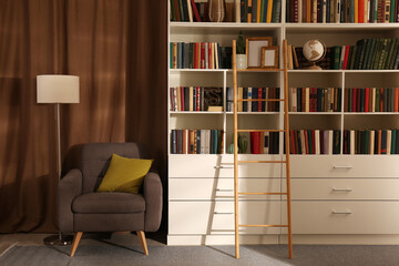 Cozy home library interior with collection of different books on shelves and comfortable place for reading