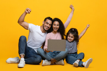 Online Win. Excited Arab Parents And Little Daughter Celebrating Success With Laptop