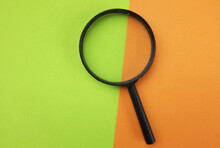 A Magnifying Glass On Two Tone The Green And Orange Background