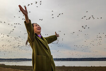 Young Woman With Birds Flying Over Beach