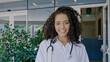 Latin young female doctor wear white uniform, white medical coat, stethoscope and looking at camera