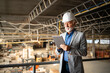 © littlewolf1989 - Factory CEO or manager in business suit and hardhat standing in production hall and checking results of his company. Industrial factory interior and forklifts working in background.