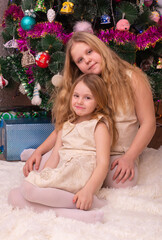 Wall Mural - Two beautiful little sisters near the Christmas tree.