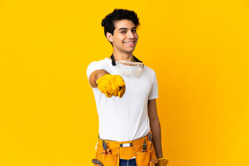 Venezuelan electrician man isolated on yellow background pointing front with happy expression