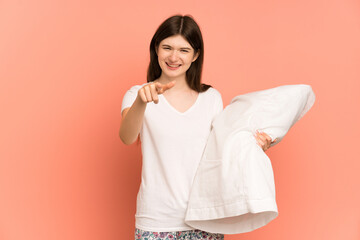 Young Ukrainian girl isolated on pink background in pajamas and points finger at you with a confident expression