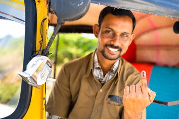 focus on finger, smiling auto driver showing ink marked finger after voting in election by looking a