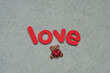The word love with a small little bear on a white background