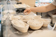 © dsheremeta - Baker woman sprinkles flour on the shaped loaves, rustic style, bread before baking, rustic whole grain bread.