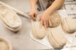© dsheremeta - women's hands make an incision on a round dough before baking bread.