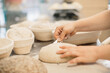 © dsheremeta - women's hands make an incision on a round dough before baking bread.